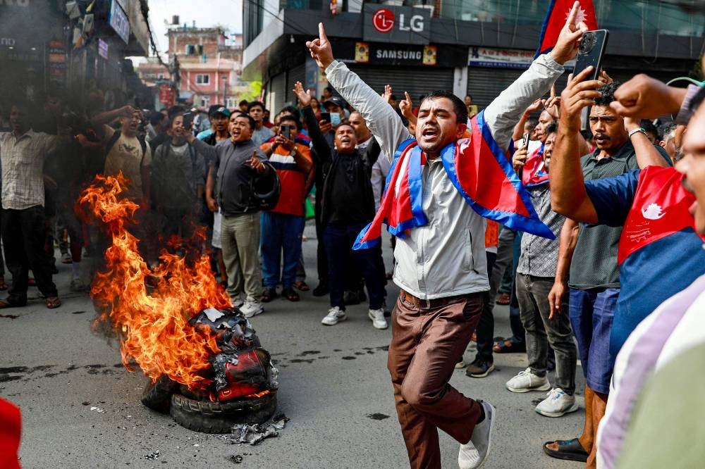 People displaying Nepal's national flag burn Tyres during a demonstration to condemn the police's deadly crackdown on protesters in Kathmandu on September 9, 2025, (AFP)