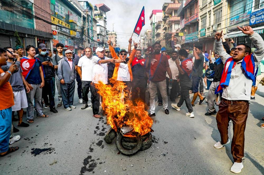 People displaying Nepal's national flag burn tyres during a demonstration to condemn the police's deadly crackdown on protesters in Kathmandu on September 9, 2025, (AFP)