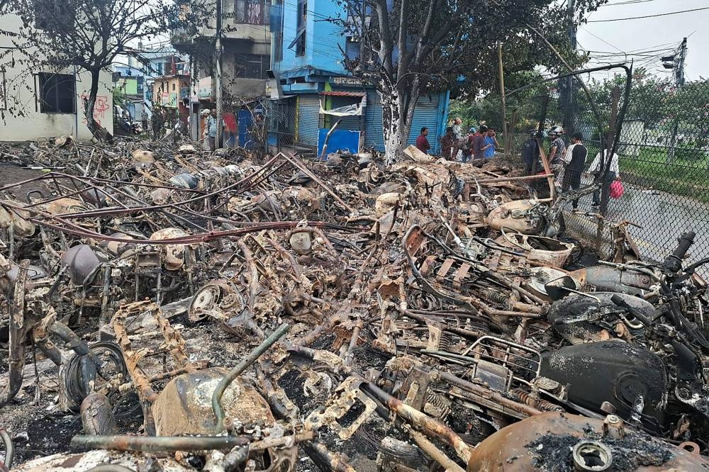 Locals stand near the charred remains of vehicles in Kathmandu on Wednesday. AFP