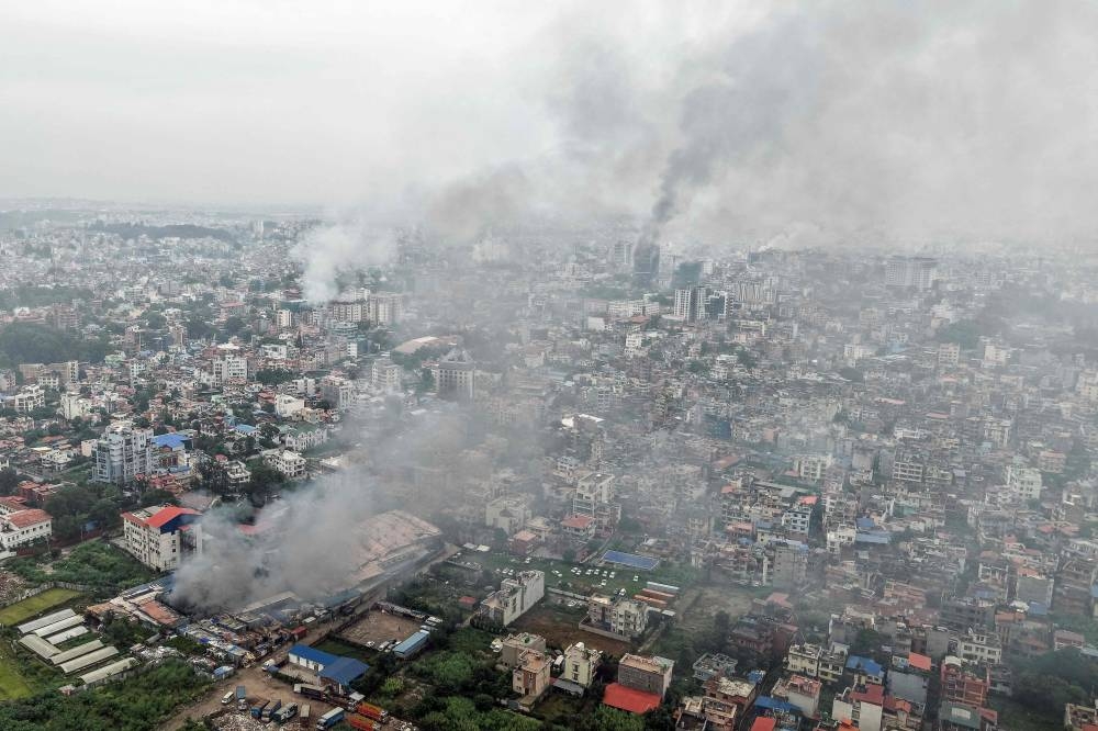 Plumes of smoke engulfs the city of Kathmandu on Wednesday, a day after several buildings were set ablaze by protesters. AFP