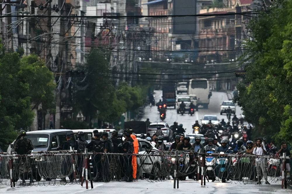 Commuters make their way behind the barricades along a street near the Nepal's President House in Kathmandu on Friday. AFP