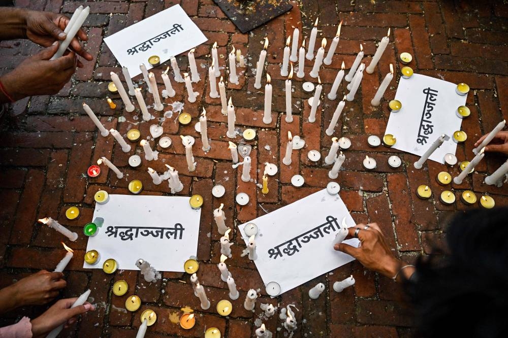 People light candles beside posters reading 'shraddhanjali' meaning 'condolences' during a silent tribute held for victims killed in the clashes against police personnel, at the Boudhanath Stupa in Kathmandu, on Saturday. AFP