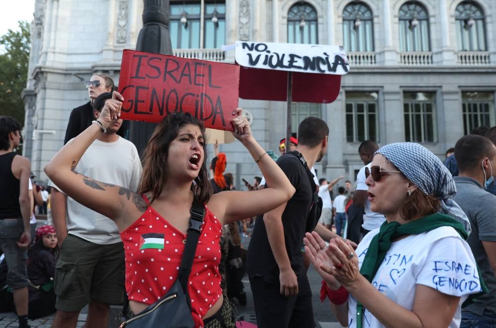 Pro Palestine protester with a banner above her head during Vuelta a Espana Stage 21. REUTERS