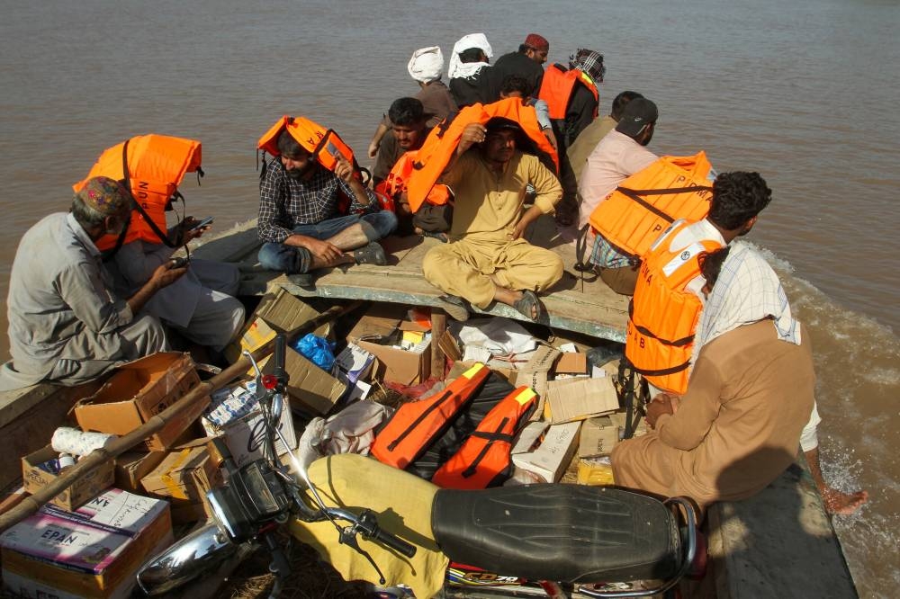 People, including government officials, travel in a boat with medical aid for the flood victims, following monsoon rains and rising water levels of the Chenab River, in Seetpur, Punjab province, Pakistan, 2025. REUTERS