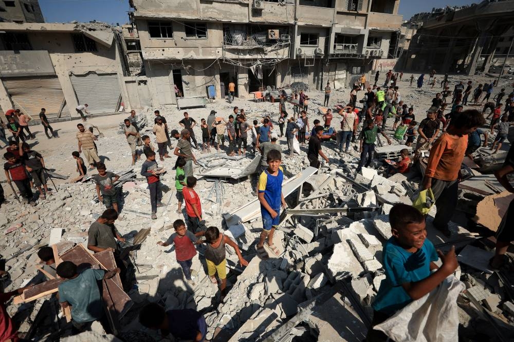 Palestinians gather at the site of Israeli air strikes on the evacuated Al-Ghefari tower, in Gaza City. REUTERS