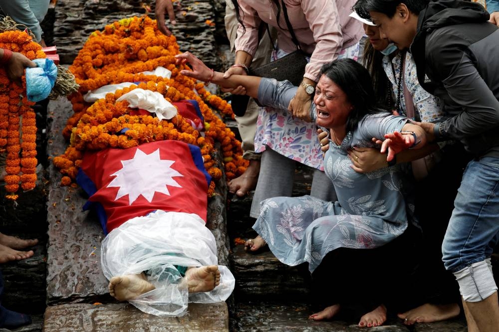 Mother of Rashik Khatiwada, 23, who died in last week's anti-corruption protests that toppled the government, mourns during the cremation rituals at the premises of Pashupatinath temple, along the bank of Bagmati river, in Kathmandu, Nepal, on Tuesday. REUTERS