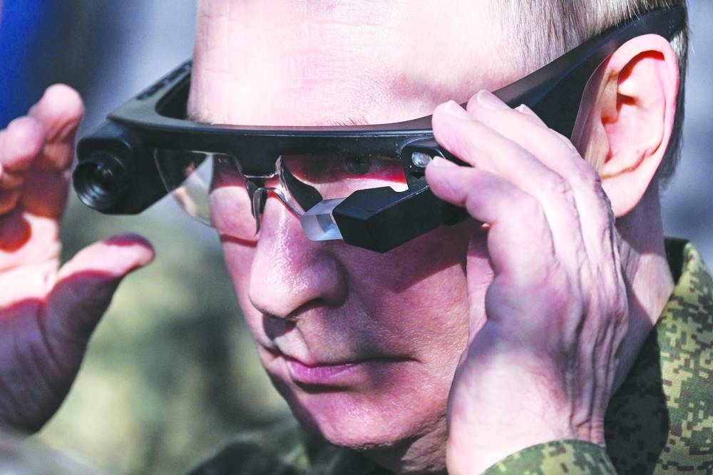 Russian President Vladimir Putin tries on a thermal imaging glasses during the tour of the exhibition of military equipment. AFP
