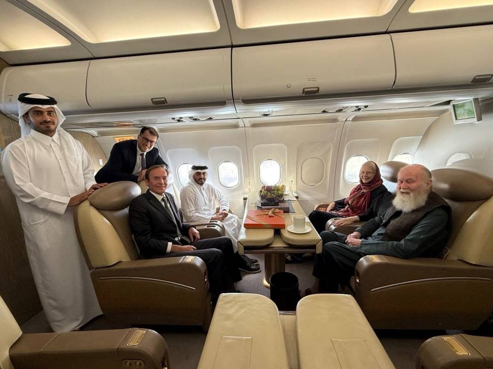 British citizens named Peter and Barbara Reynolds, who had been in custody in Afghanistan, sit with Qatari and British diplomats, on an aircraft, in the air, on Friday. 