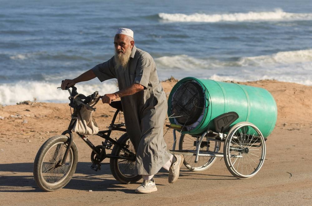 A displaced Palestinian man, fleeing northern Gaza due to an Israeli military operation, walks with his  belongings as people move southwards after Israeli forces ordered residents of Gaza City to evacuate to the south, in the central Gaza Strip, on Saturday. REUTERS