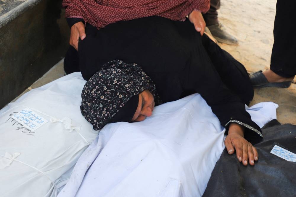 A relative embraces body bags, during the funeral for members of the Abu Amsha family, who were killed in an Israeli strike on a house on Saturday amid their military operation, according to medics, at Al-Shifa Hospital in Gaza City, September 21, 2025. REUTERS