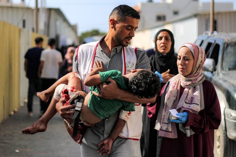 A worker at al-Awda Hospital carries a child who was injured by reported Israeli bombardment on al-Bureij, outside the hospital facility in Nuseirat in the central Gaza Strip, on Sunday. AFP
