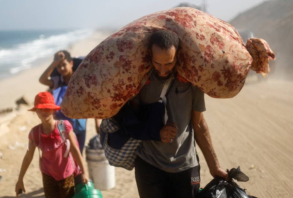 Displaced Palestinians, fleeing northern Gaza due to an Israeli military operation, move southward, carrying personal belongings, after Israeli forces ordered residents of Gaza City to evacuate to the south, in the central Gaza Strip, on Sunday. REUTERS