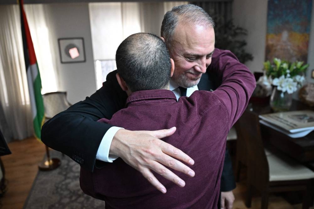 Head of the Palestine Mission to the UK, Husam Zomlot (R) embraces members of staff after watching a television broadcast of Britain's Prime Minister Keir Starmer formally recognising The Palestinian State on Sunday at their Mission in west London. AFP