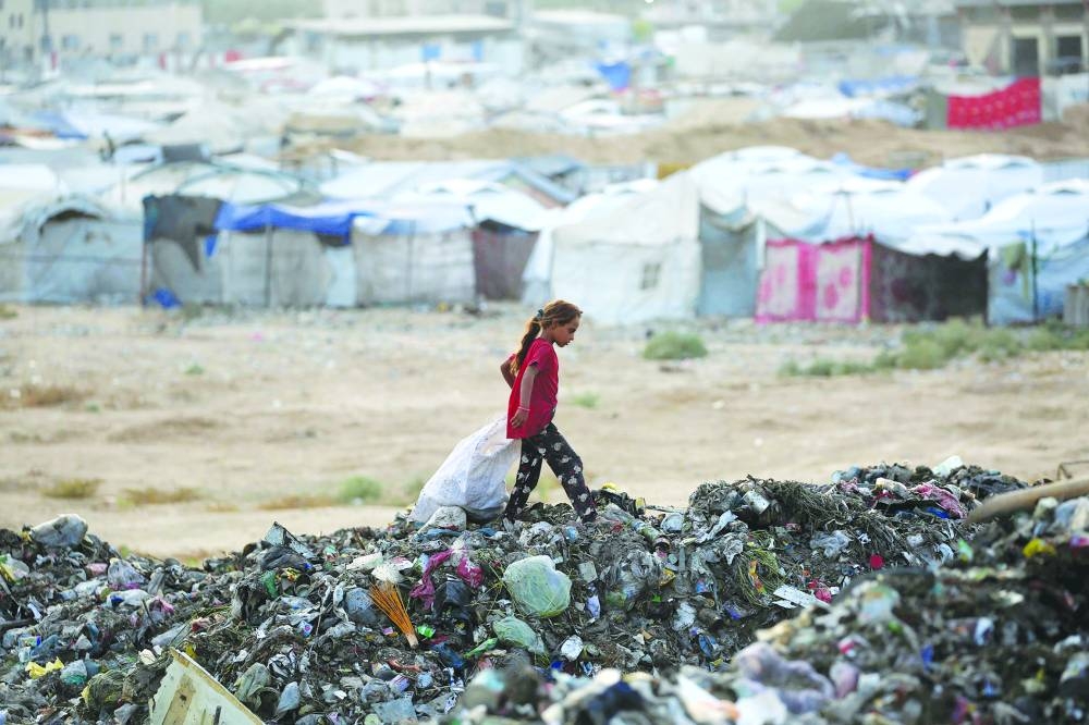 A girl sifts through the rubbish near tents and makeshift shelters at the Bureij camp for refugees in the central Gaza Strip on Sunday. AFP