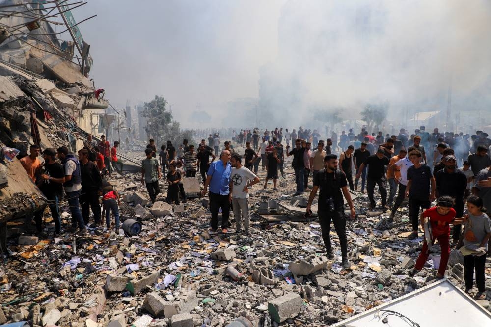 Palestinians gather at the site of Israeli strikes on residential buildings, amid an Israeli military operation, in Gaza City, on Monday. REUTERS