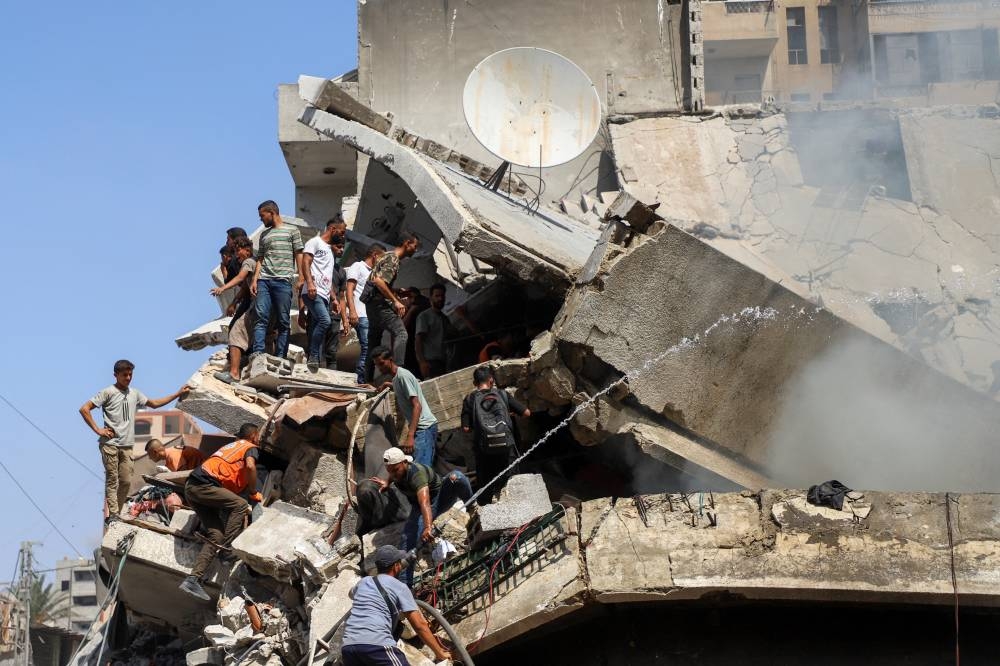 Palestinians search for victims at a residential building hit in an Israeli strike, amid an Israeli military operation, in Gaza City, on Monday. REUTERS