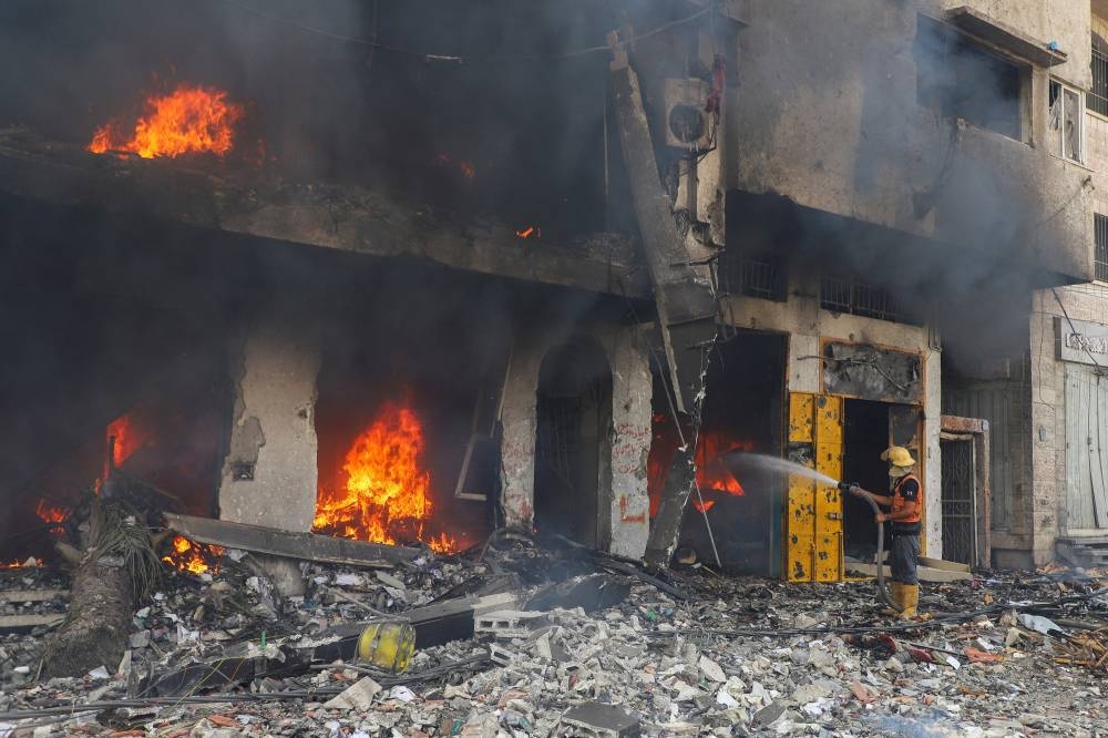 A Palestinian firefighter tries to extinguish fire at a residential building hit in an Israeli strike, amid an Israeli military operation, in Gaza City, on Monday. REUTERS