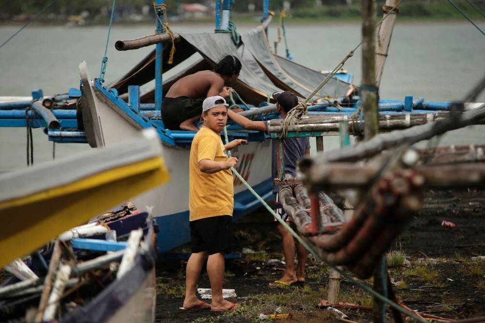 Residents secure their fishing boats at a village in Legaspi City, Albay province, south of Manila, on September 25, 2025, ahead of Tropical Storm Bualoi's landfall in the Bicol region. The Philippines shut schools and scrapped flights on September 25 as a fresh storm threatened to hit just days after a super typhoon killed nine people in the archipelago. (Photo by CHARISM SAYAT / AFP)