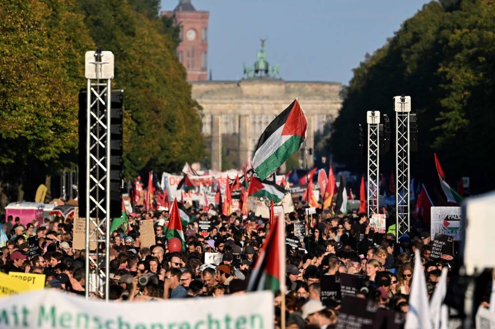 Participants march with Palestinian flags during a demonstration near the Brandenburg Gate in the center of Berlin.