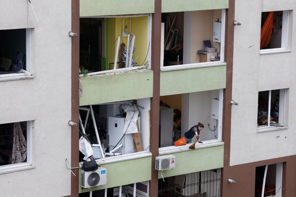 A resident cleans her apartment at an impact site in a residential neighbourhood after Russian drone and missile attacks in Kyiv, Ukraine, September 28, 2025. REUTERS