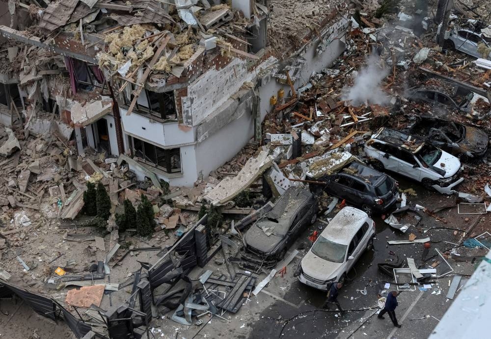 People walk next to a damaged building and vehicles in a residential neighbourhood hit during a Russian drone and missile strike, amid Russia's attack on Ukraine, on the outskirts of Kyiv, Ukraine, on Sunday. REUTERS