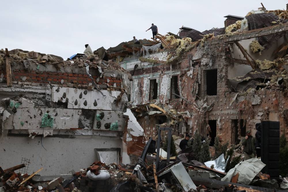 People inspect the damage as they stand on top of a destroyed building at an impact site in a residential neighbourhood after Russian drone and missile attacks in Kyiv, on Sunday. REUTERS