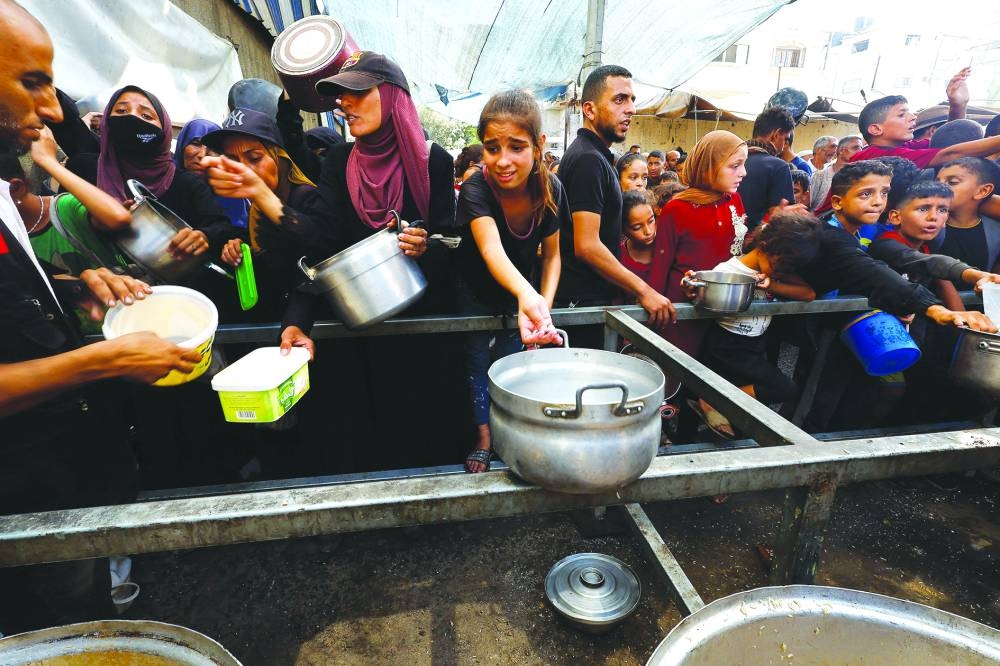 Palestinians gather to receive food from a charity kitchen, in Nuseirat, central Gaza Strip, on Sunday. REUTERS