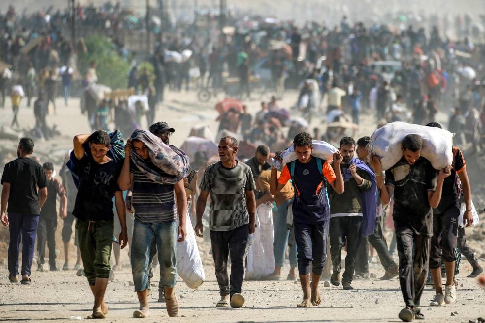People walk with humanitarian aid packages that they received from a distribution centre run by the US and Israeli-backed Gaza Humanitarian Foundation (GHF), at the so-called "Netzarim corridor", in Nuseirat in the central Gaza Strip, on Tuesday. AFP