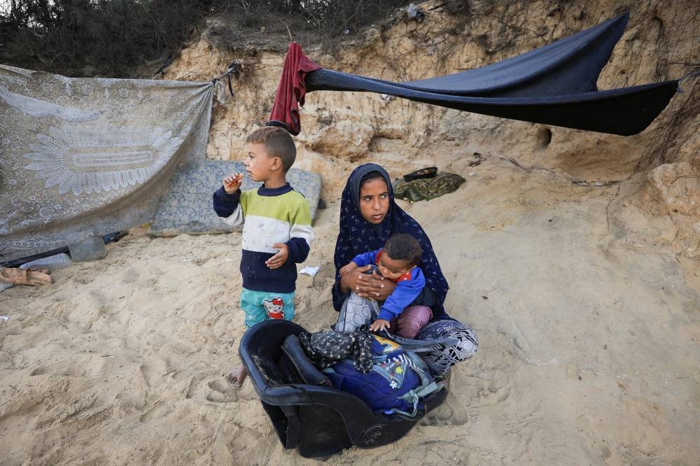 Displaced Palestinians, who fled northern Gaza after Israeli forces ordered residents of Gaza City to evacuate to the south amid an Israeli military operation, rest next to their belongings as they temporarily take shelter on a roadside, in the central Gaza Strip, on Tuesday. REUTERS