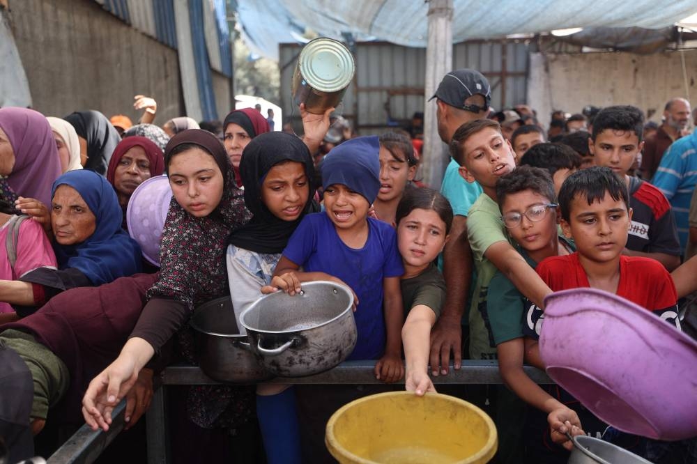 Palestinians gather to receive food portions from a charity kitchen in Nuseirat, in the central Gaza Strip, on Tuesday. AFP