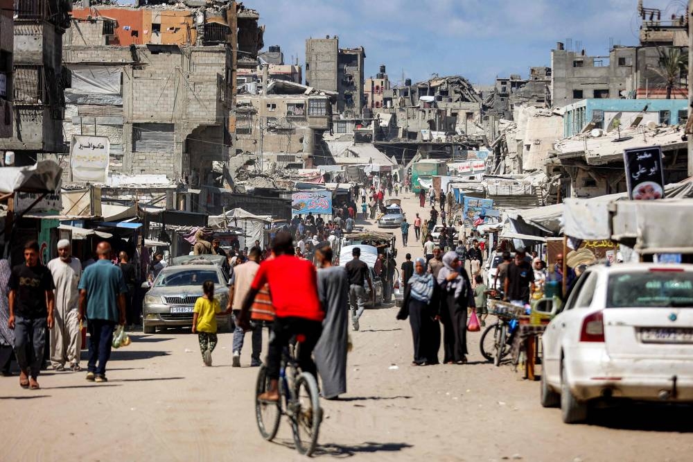 People walk past damaged buildings along a street in Khan Yunis in the southern Gaza Strip, on Tuesday. AFP