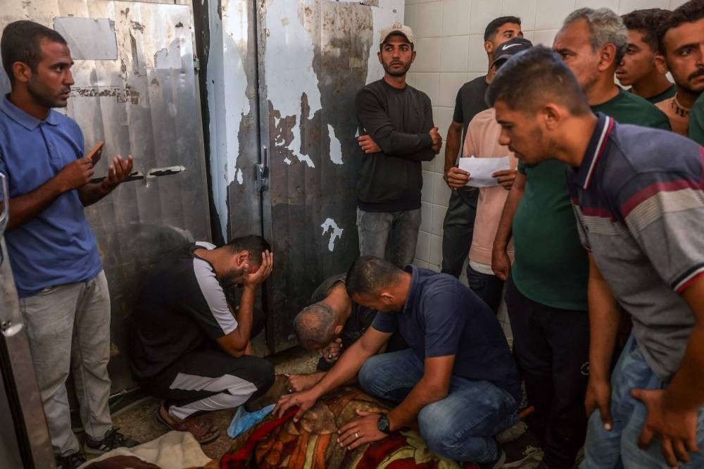 Palestinian men surround the bodies of people killed in Israeli strikes, at the morgue of al-Aqsa Martyrs hospital in Deir el-Balah in the central Gaza Strip, on October 1, 2025. The Israeli military said it will close on October 1 the last remaining route for residents of southern Gaza to access the north, as it presses its offensive on Gaza City. (AFP)