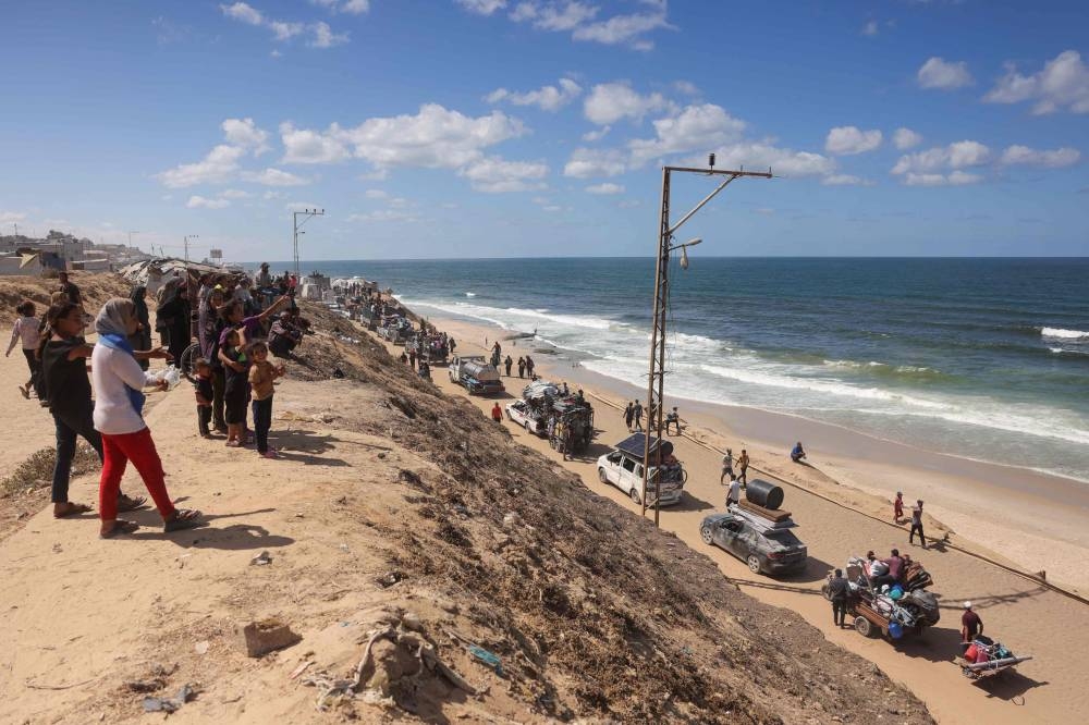 Palestinians carrying belongings arrive on a coastal path northwest of Nuseirat refugee camp as they are displaced southward from Wadi Gaza following an Israeli announcement of closing Al-Rashid road towards the north of the besieged Gaza Strip, on Wednesday. AFP