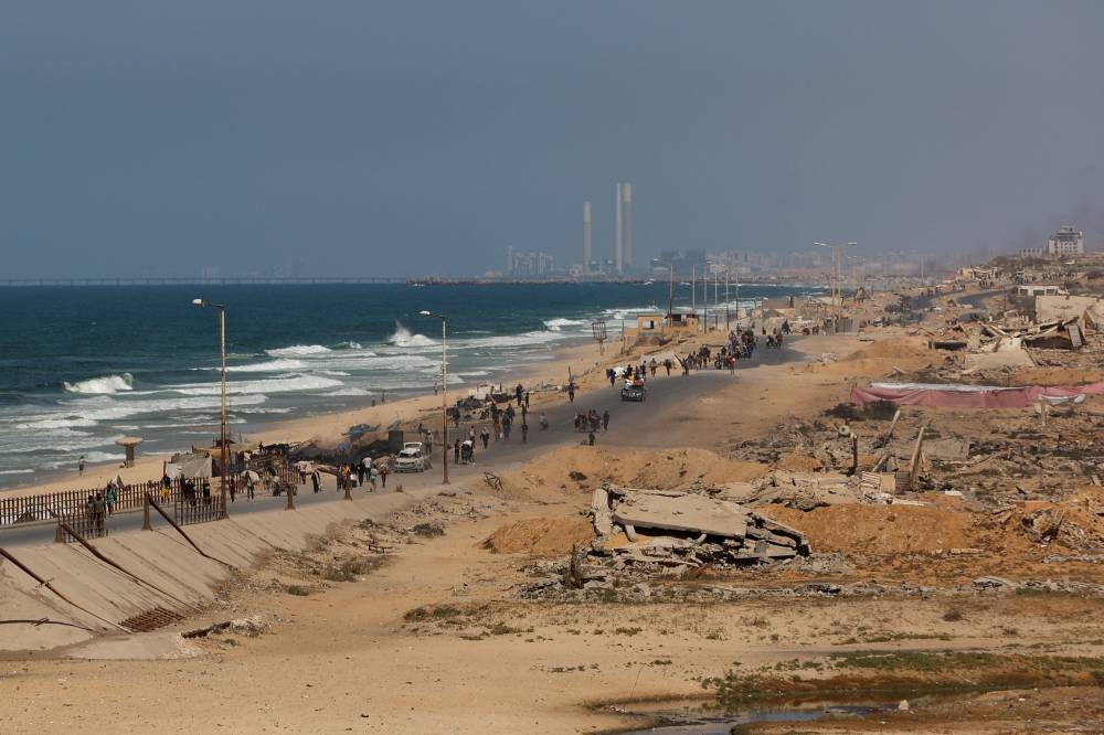 Palestinians walk on a coastal path northwest of Nuseirat refugee camp as they are displaced southward from Wadi Gaza following an Israeli announcement of closing Al-Rashid road towards the north of the besieged Gaza Strip on October 2, 2025. Israel's defence minister issued a final warning for Gaza City residents to flee south on October 1, as the Palestinian Hamas movement weighed the latest US plan to end nearly two years of war in the Palestinian territory. (Photo by Omar AL-QATTAA / AFP)