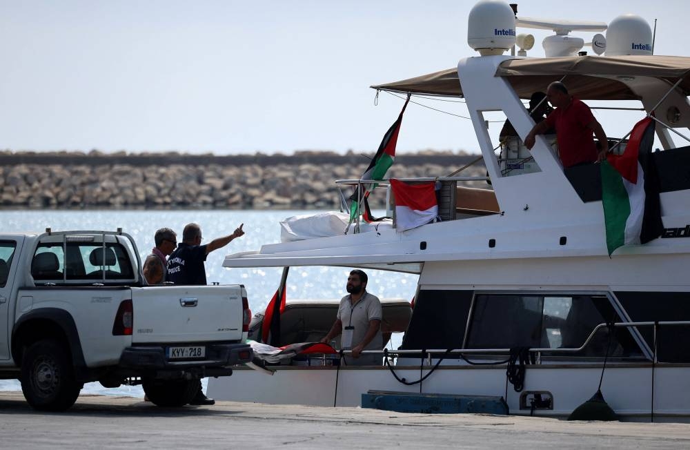A police officer talks to a man on a boat from a flotilla that had been carrying aid to Gaza until it was intercepted by Israel, docked in the port of Larnaca, on Friday. REUTERS