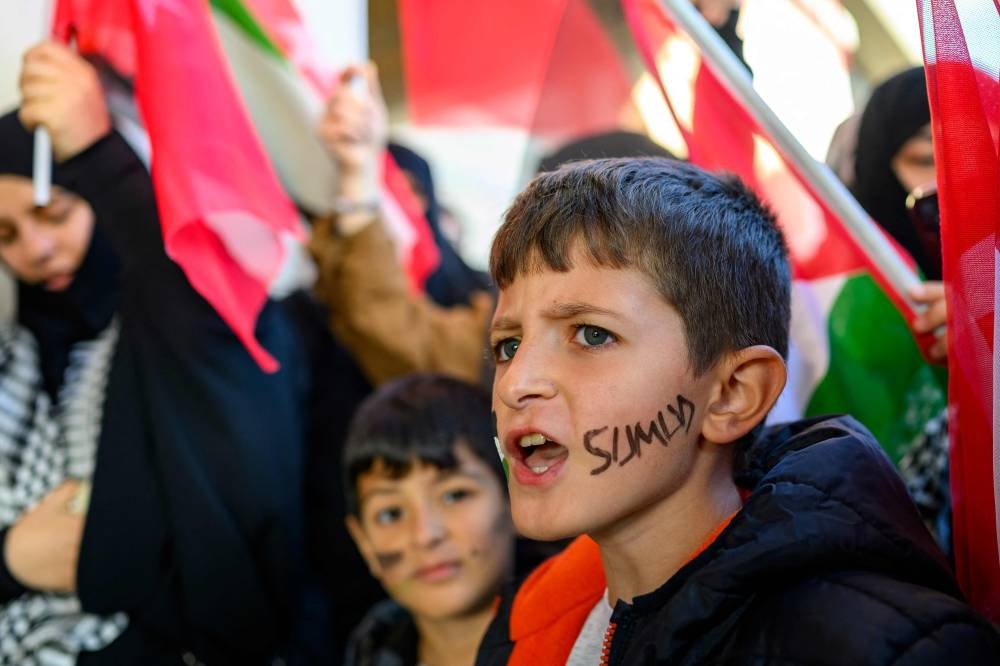 Children wave Turkish and Palestinian flags as people wait for the arrival of thirty-six Turks and nationals from 12 countries who were due to arrive at Istanbul Airport on a special flight after Israel stopped a Gaza-bound aid flotilla and detained hundreds of people, in Istanbul, on Saturday. AFP