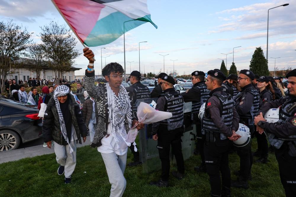 A Malaysian activist, on of those who were sailing aboard vessels from the Global Sumud Flotilla, which were seized by Israeli forces, carries a Palestinian flag after arriving at Istanbul Airport on a special flight, in Istanbul, on Saturday. REUTERS