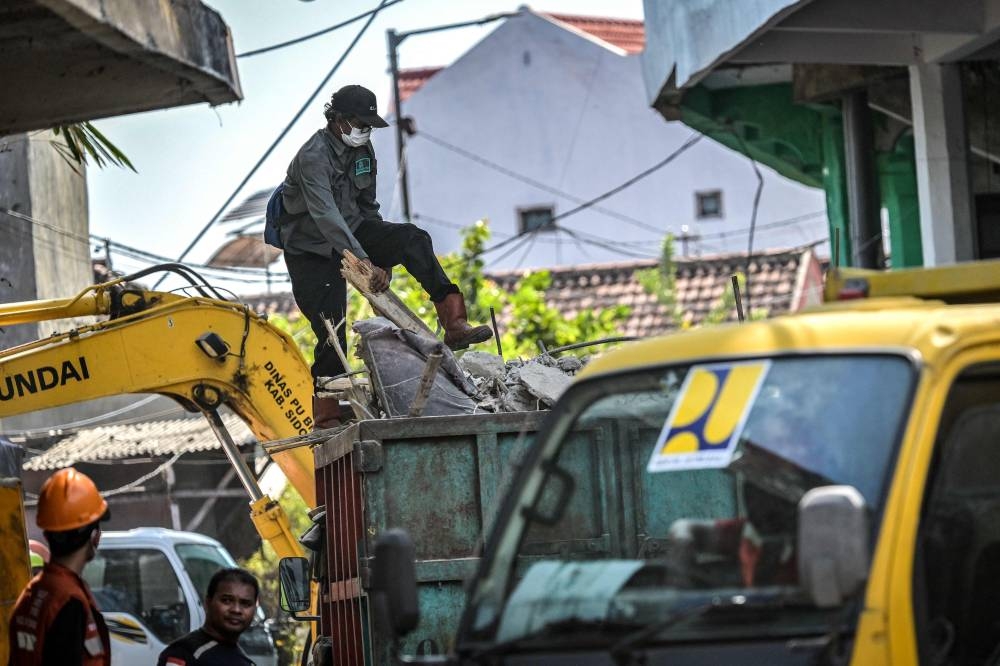 A man loads debris onto a truck from the site of the collapsed Al Khoziny Islamic boarding school in Sidoarjo, East Java, on Sunday. AFP