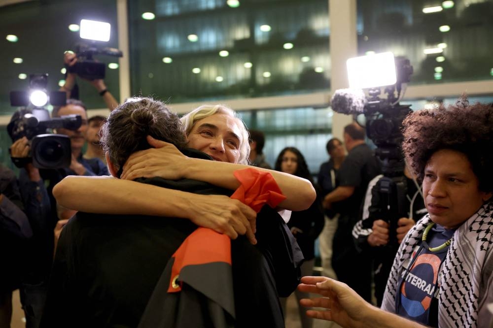 Former Barcelona mayor Ada Colau, who was sailing aboard a vessel from the Global Sumud Flotilla, is hugged as she arrives at Barcelona's airport on Sunday. AFP