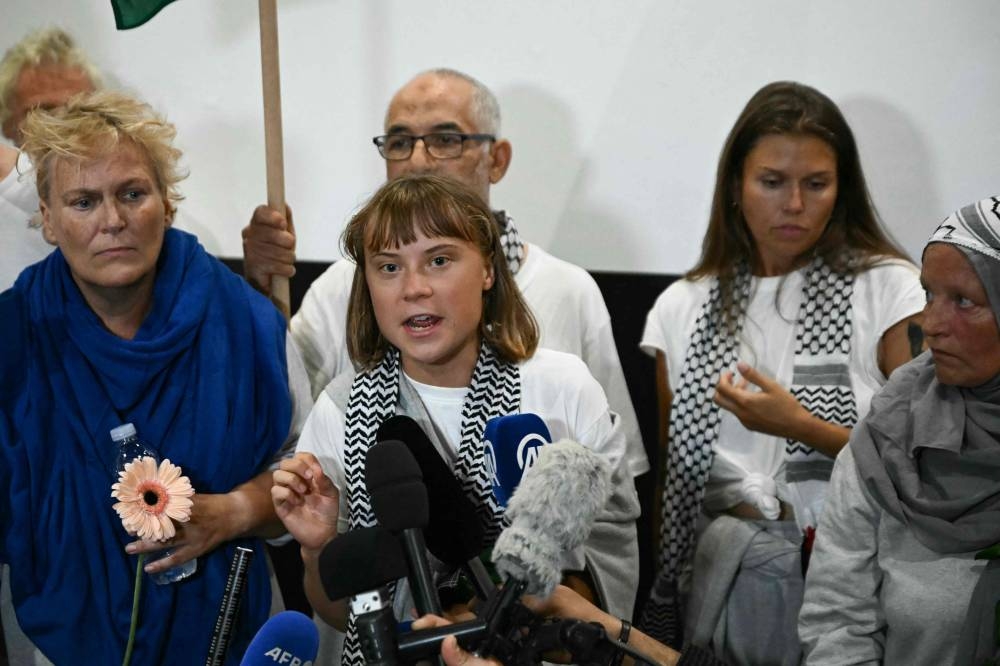 Swedish climate campaigner Greta Thunberg (C) delivers remarks upon arrival alongside activists who were sailing aboard vessels from the Gaza-bound aid flotilla, greeted by a crowd of supporters, at the arrivals area of Athens International Airport on Monday. AFP