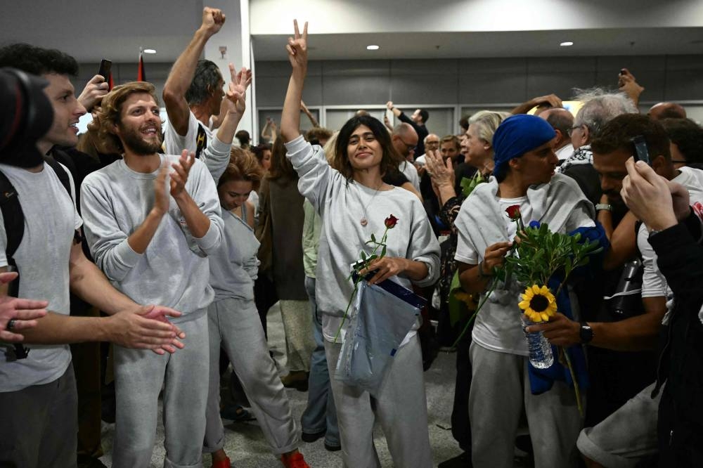 
French-Palestinian lawyer and member of European Parliament for La France Insoumise (LFI) party Rima Hassan flashes the peace sign, upon arrival alongside activists who were sailing aboard vessels from the Gaza-bound aid flotilla, greeted by a crowd of supporters, at the arrivals area of Athens International Airport on Monday. AFP