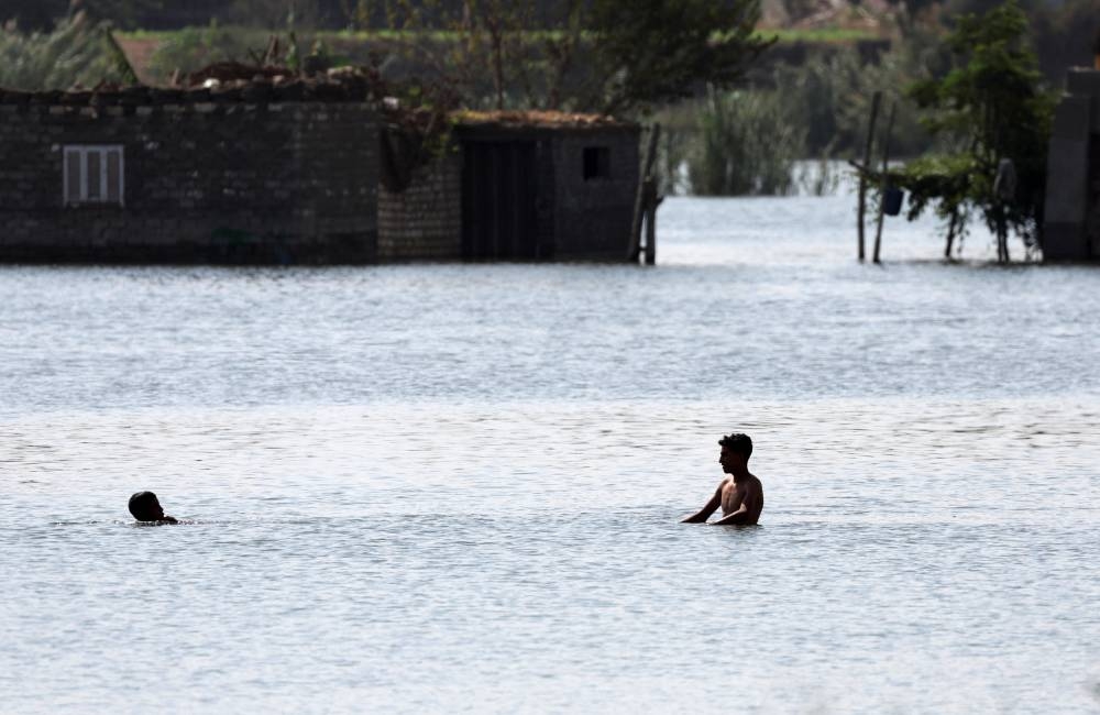 Children swim in the Nile to reach their home after flooding in Dalhamo Village, near the Delta city of Ashmoun, in Menoufia Governorate, Egypt, on Sunday. REUTERS