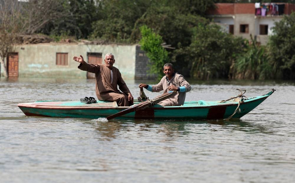 Two men row their boat after flooding in Dalhamo Village, near the Delta city of Ashmoun, in Menoufia Governorate, Egypt, on Sunday. REUTERS