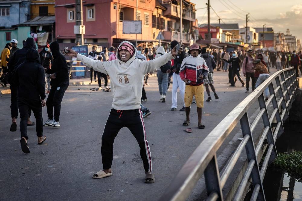 A protester reacts as he hold stones during clashes with Malagasy security forces at a demonstration calling for the resignation of President Andry Rajoelina, in Antananarivo, on Sunday. AFP