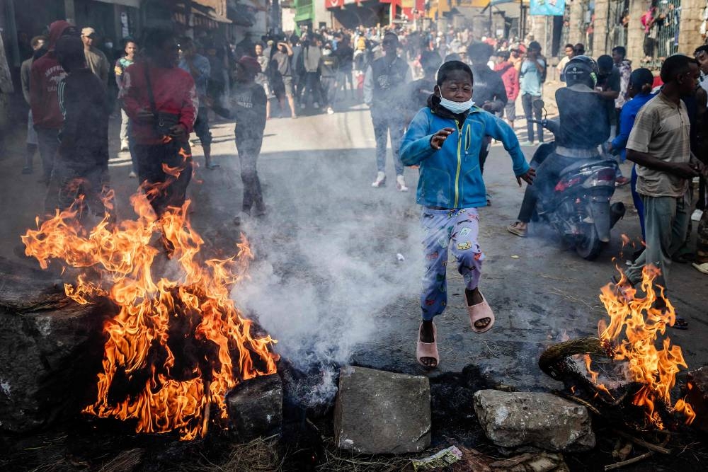 A young boy jumps over a burning barricade set up by students during clashes between protesters and security forces at a demonstration calling for the resignation of President Andry Rajoelina, in Antananarivo, on Sunday. AFP