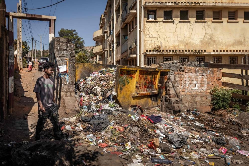 A student walks past a pile of garbage accumulated in front of the university dormitories at the University of Ankatso in Antananarivo, on Wednesday. AFP