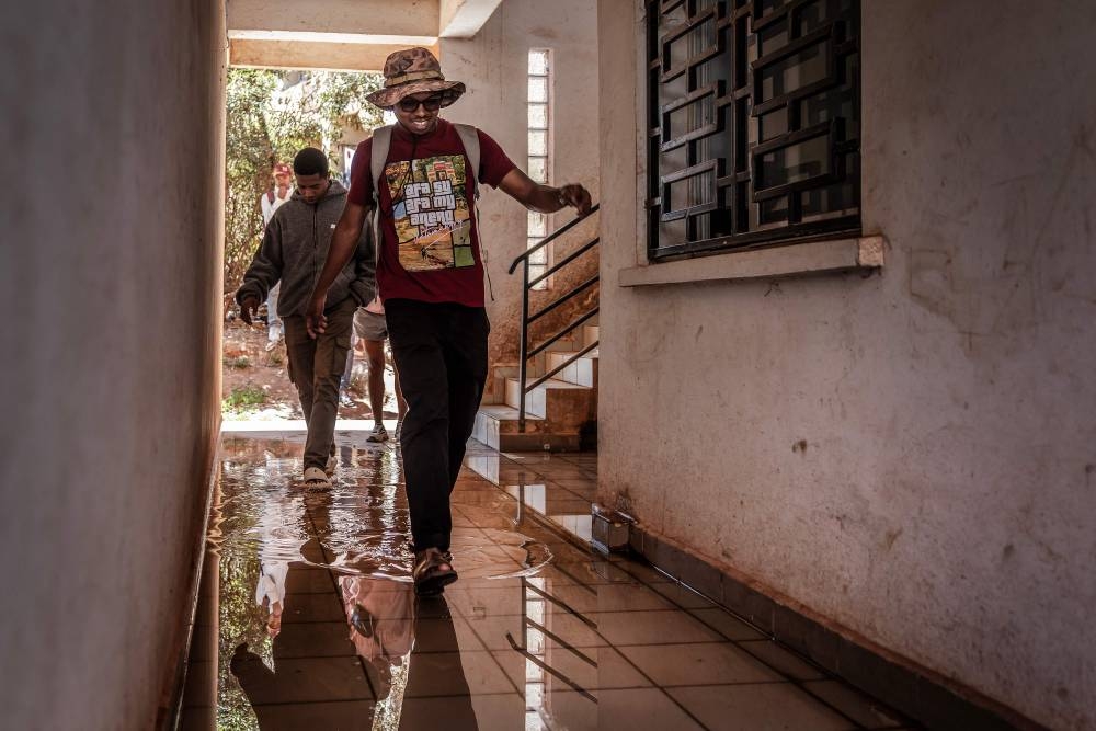 Ulric Zambisafy, 24 (C), a student at the University of Ankatso, walks through a corridor flooded with water inside a deteriorating dormitory, followed by fellow student Ezechiel Ledy, 26 (L), at a dormitory affected by recurring water and power shortages in Antananarivo, on Wednesday. AFP