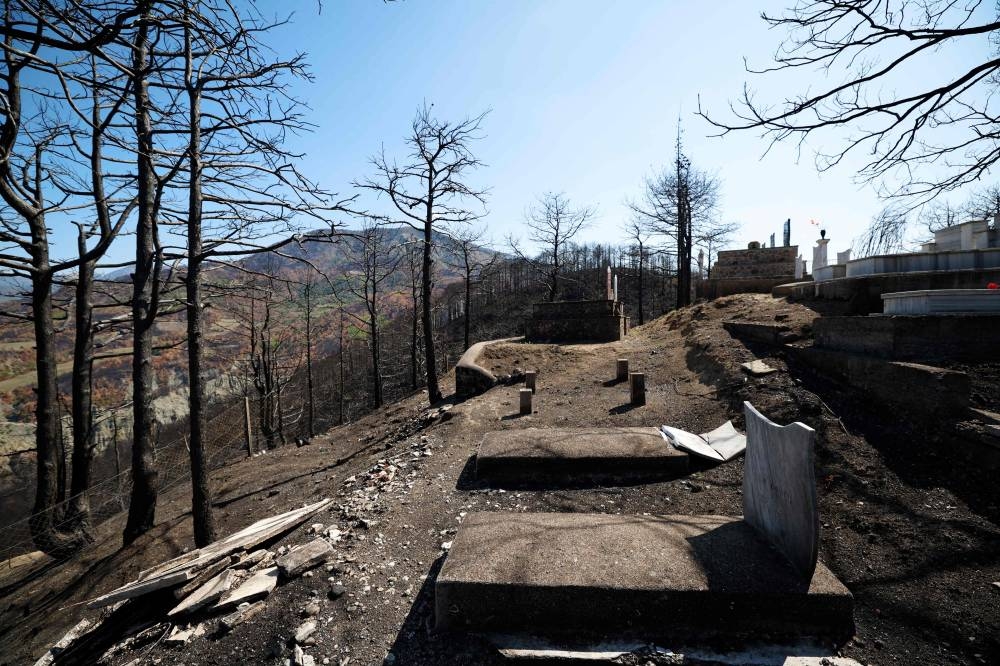 This photograph shows a damaged cemetery in a burned forest, in Skenderbegas, near Gramsh, on September 16, 2025. Weeks of violent wildfires have devastated pine forests around Skenderbegas in central Albania’s Gramsh region, destroying more than 700 hectares of woodland and dozens of homes with livestock and wildlife among the victims, as the country faced extreme heat and drought on summer 2025, making it one of the Balkan nations most affected by wildfires. (AFP)