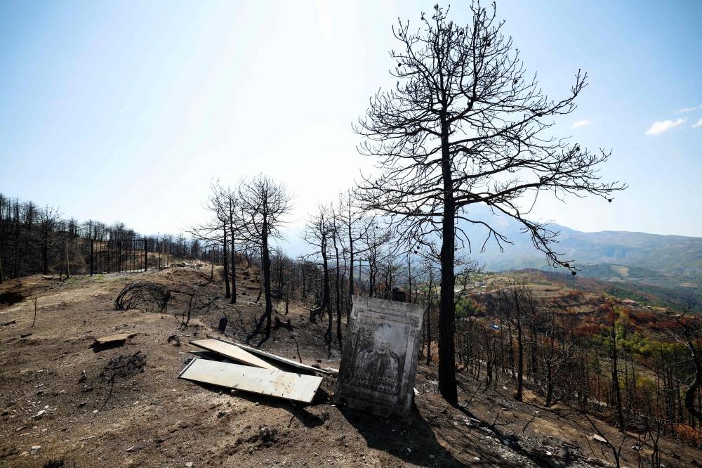 This photograph shows a damaged cemetery in a burned forest, in Skenderbegas, near Gramsh, on September 16, 2025. Weeks of violent wildfires have devastated pine forests around Skenderbegas in central Albania’s Gramsh region, destroying more than 700 hectares of woodland and dozens of homes with livestock and wildlife among the victims, as the country faced extreme heat and drought on summer 2025, making it one of the Balkan nations most affected by wildfires. (AFP)