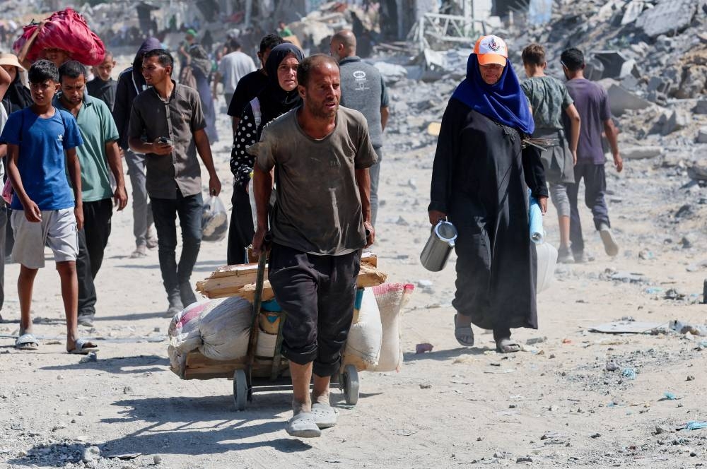 Palestinians walk past the rubble following Israeli forces' withdrawal from the area, after Israel and Hamas agreed on the Gaza ceasefire, in Khan Younis, in the southern Gaza Strip, October 10, 2025. REUTERS